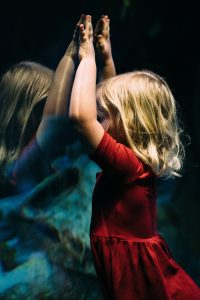 Young girl looking up close at herself in a mirror.