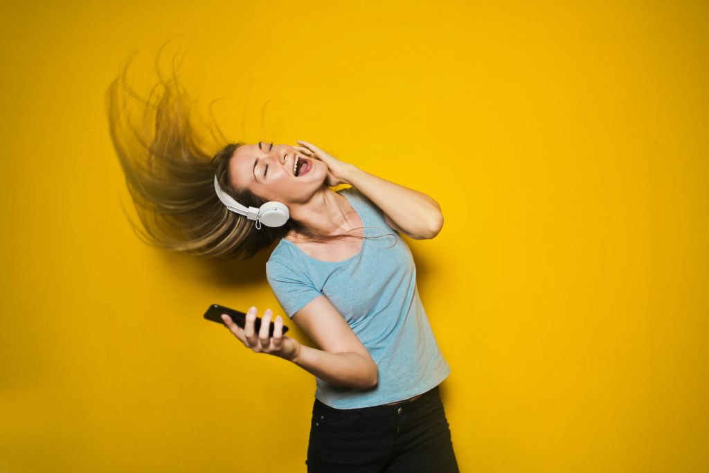 Woman dancing it out with headphones and a smart phone.