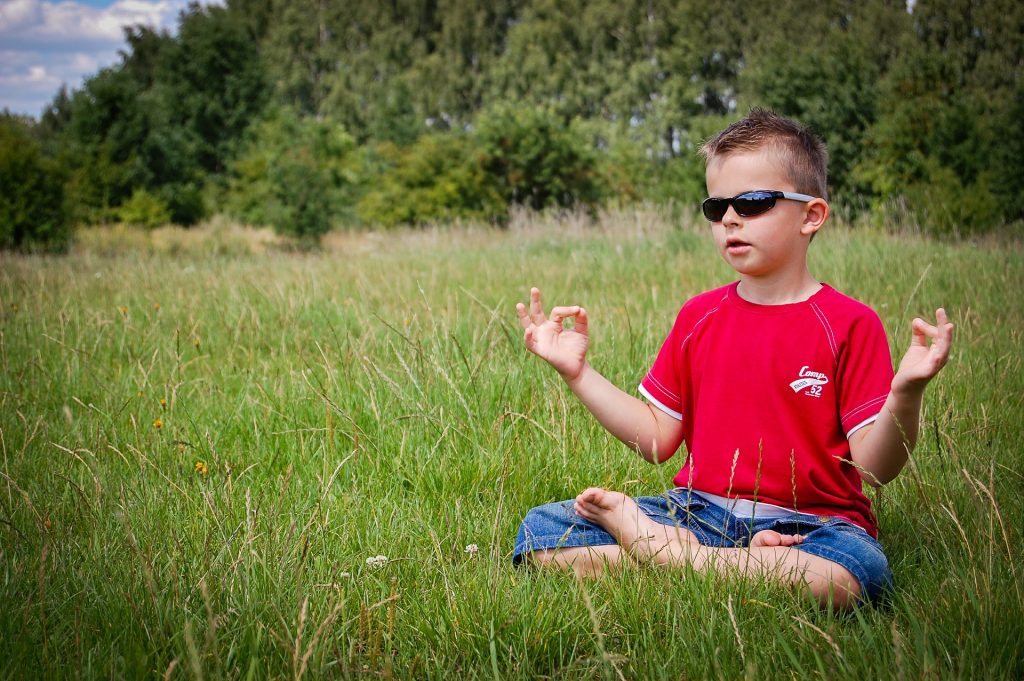 Young boy meditating in a field.